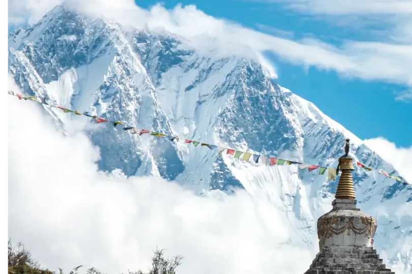 Snow-covered Himalayan mountain and Buddhist stupa with prayer flags in Nepal