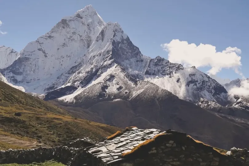 Snow-capped Himalayan mountain and stone shelter on a July trek in Nepal