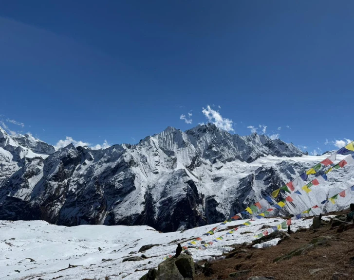Colorful Buddhist prayer flags overlooking snow-covered Himalayan peaks during the Langtang Gosaikunda Trek in Nepal.