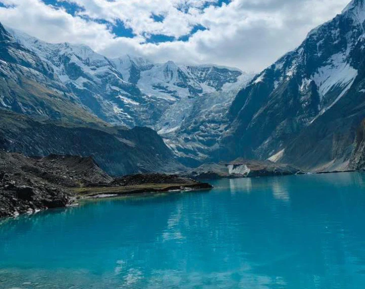 Turquoise glacial lake at North Annapurna Base Camp surrounded by snow-capped Himalayan peaks, glaciers, and a dramatic alpine landscape.