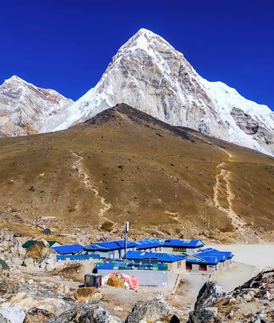 Pumori Mountain rising above Gorak Shep with teahouses, trekking trails, and snowy Himalayan peaks in the Everest region.