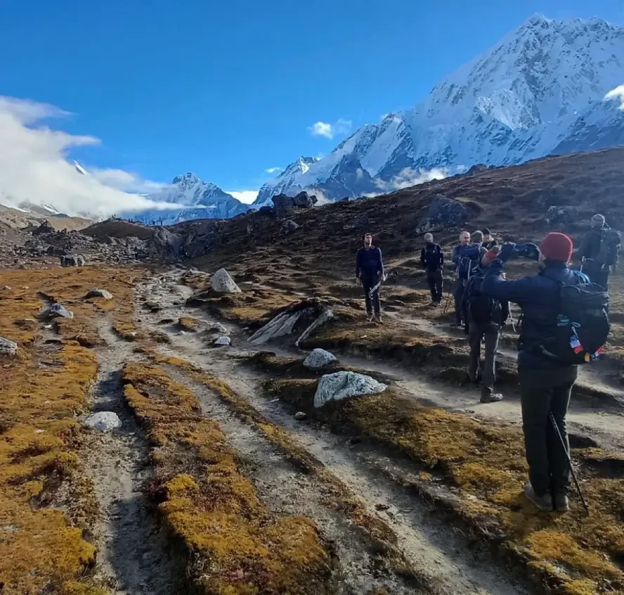 Trekkers hiking along the Everest Base Camp trail with snow-covered Himalayan peaks in Nepal.