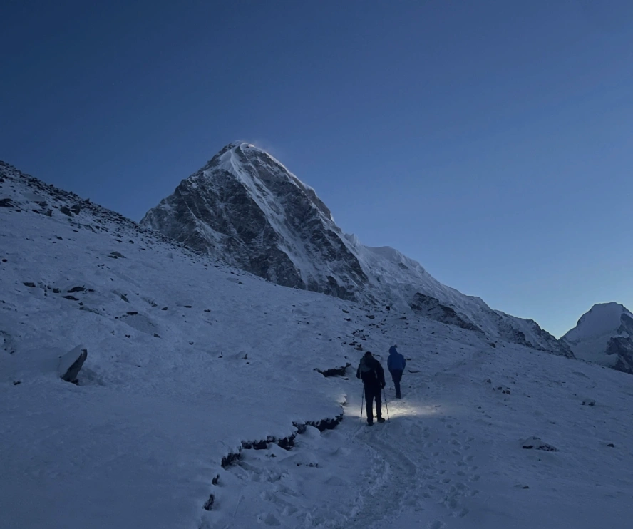 Trekkers hiking through snow near Kala Patthar with Himalayan mountain views