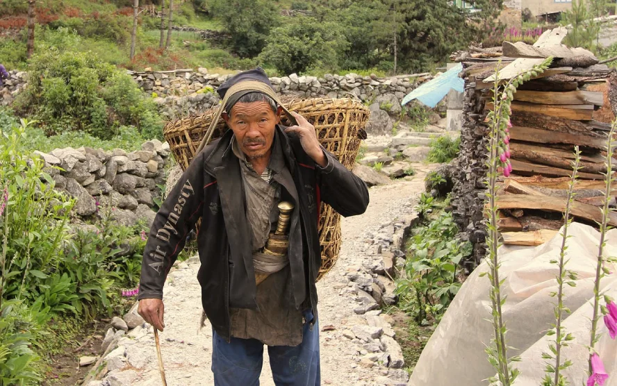 Nepalese porter carrying a basket on a mountain trail in Nepal.