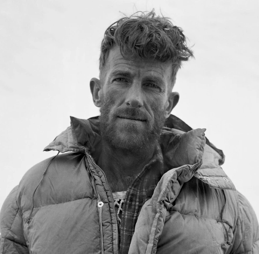 Black-and-white portrait of Sir Edmund Hillary wearing a thick down jacket, captured during a Mount Everest expedition, highlighting the determination and resilience of the legendary mountaineer.