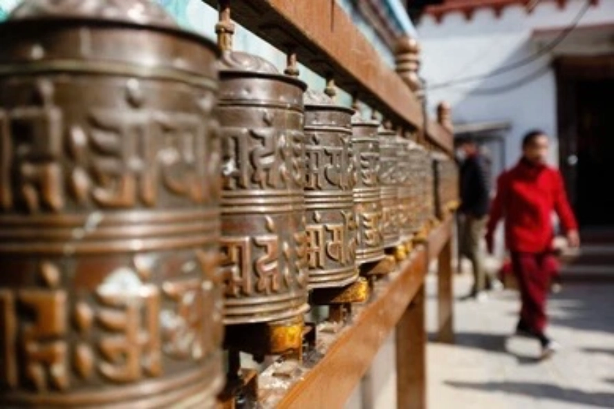 Buddhist prayer wheels and a monastery scene reflecting Sherpa religious practice in Namche Bazaar.