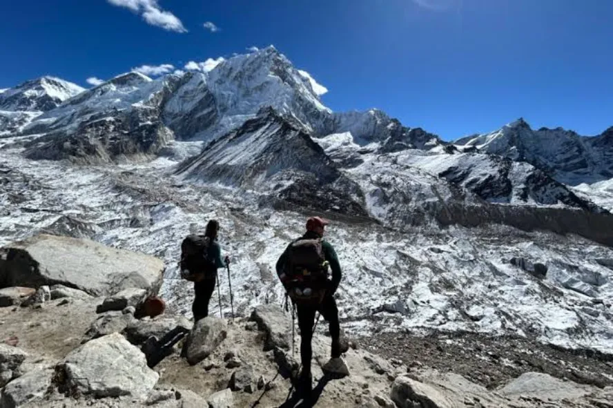 Trekkers hiking a snowy Everest Base Camp trail with snow-covered Himalayan peaks in winter